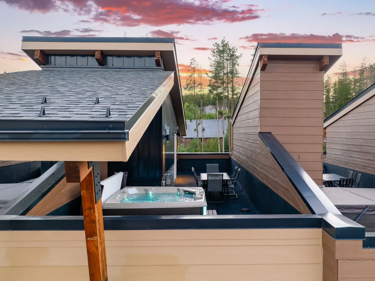A wide rooftop view showing the custom hot tub, outdoor dining space, wooden beams, and rooftop architecture. The scene is serene, inviting, and visually demonstrates the rooftop's ability to host memorable sunset gatherings and luxurious relaxation.
