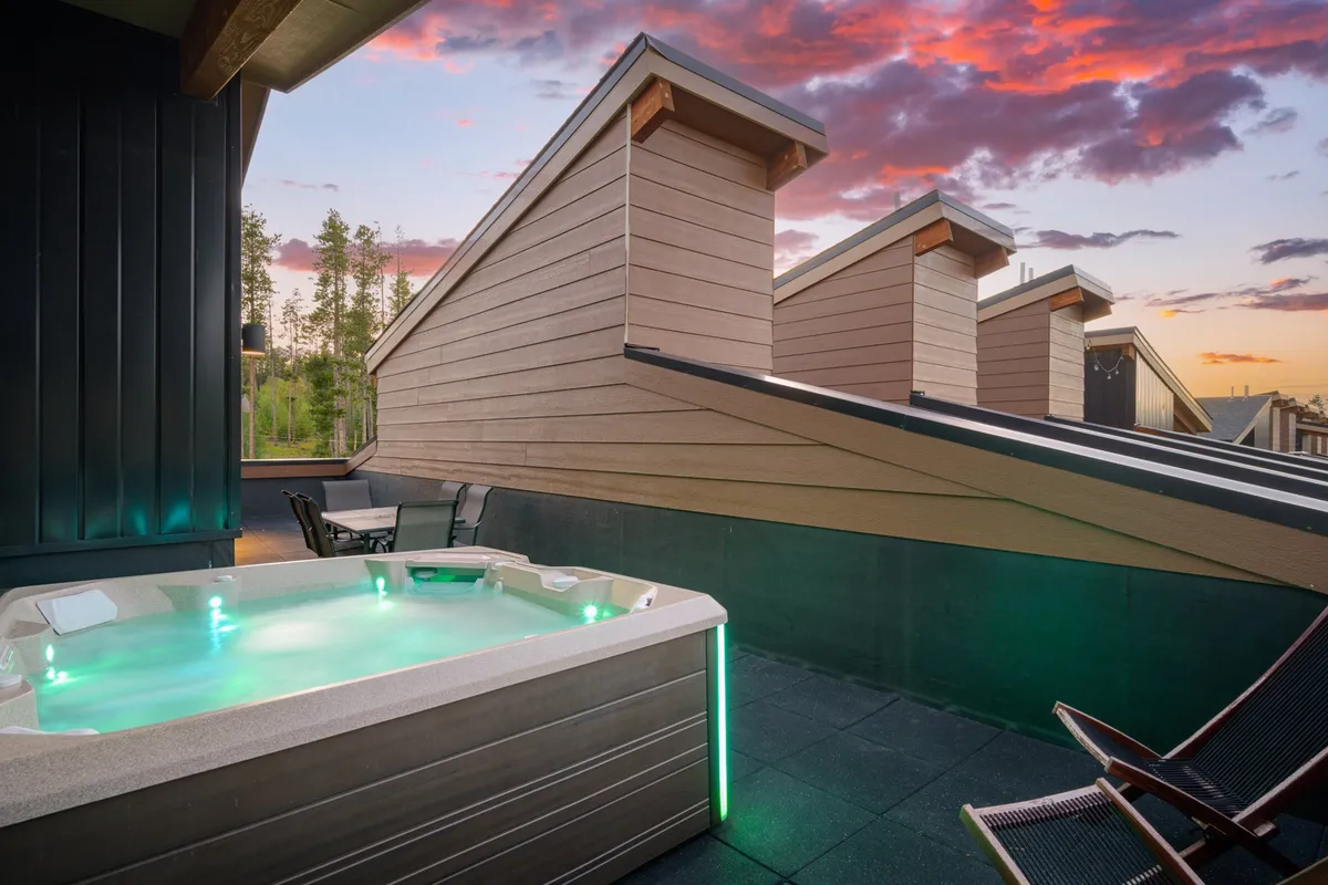 An inviting rooftop hot tub set against a colorful sky, offering panoramic mountain views. The hot tub is positioned as a relaxing retreat after a day of adventure, perfect for unwinding and connecting as a family while taking in the sunset or starry night.